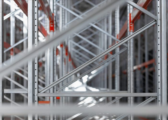 Close-up view of industrial metal shelving racks in a warehouse or factory. The steel structure with orange beams and metal efficient storage system. Logistics industrial design concepts