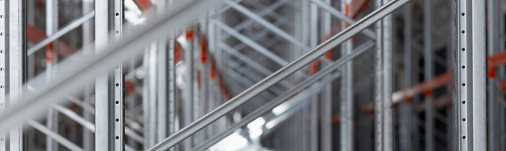 Close-up view of industrial metal shelving racks in a warehouse or factory. The steel structure with orange beams and metal efficient storage system. Logistics industrial design concepts